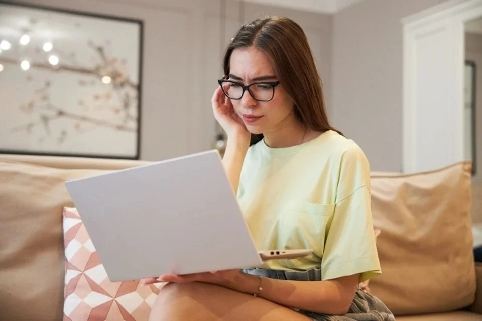 девушка в очках сидит с ноутбуком на коленях