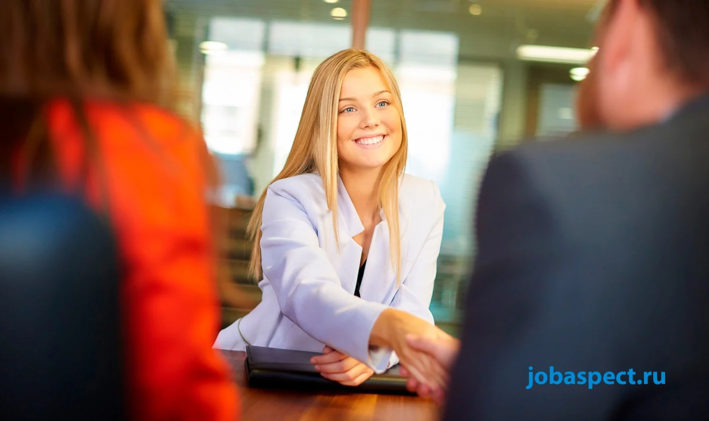 девушка проводит собеседование пожимает руку кандидату и приятно улыбается
