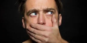 молодой человек закрывает ладонью рот