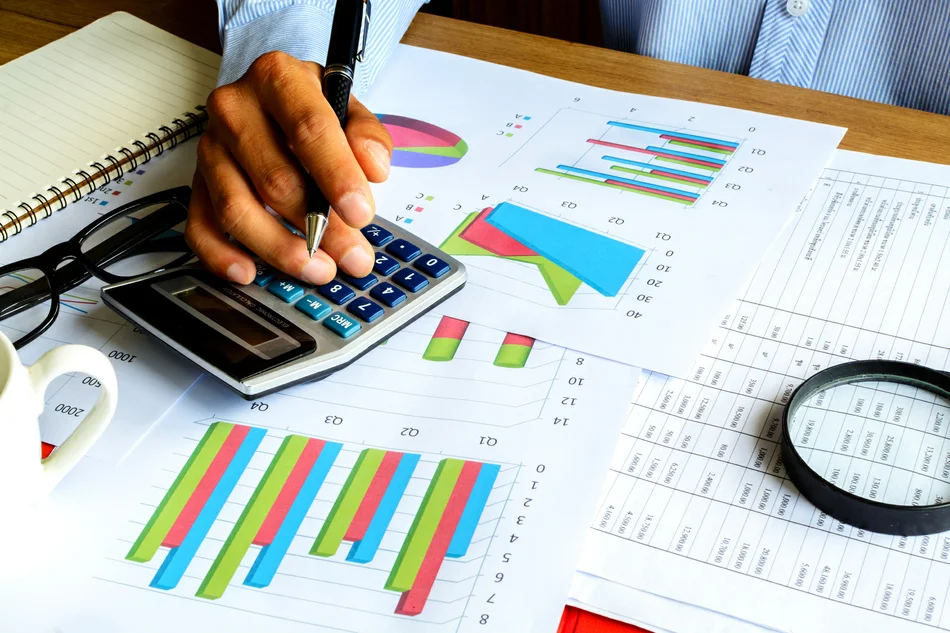 на рабочем столе калькулятор, диаграммы, таблицы, лупа