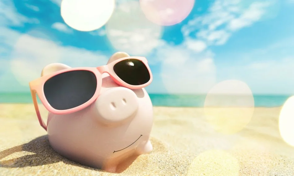 фигурка розового поросенка в солнцезащитных очках на пляже возле моря