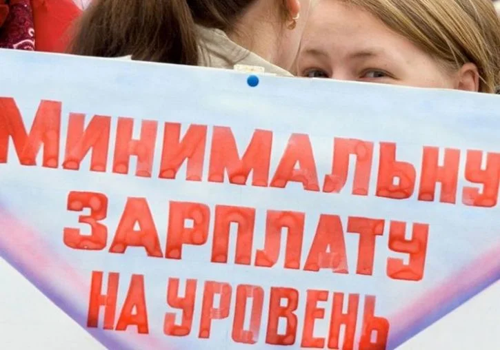 девушка с плакатом о минимальной зарплате