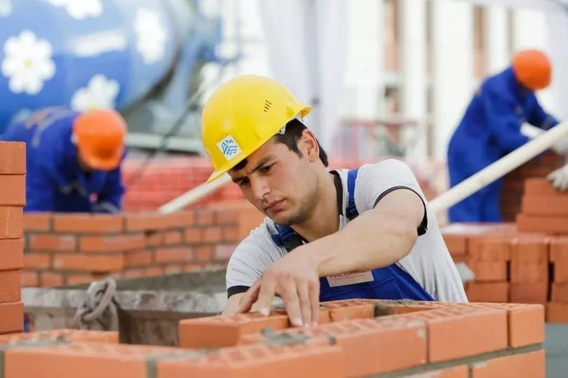 укладчик кирпича на стройке в желтой каске