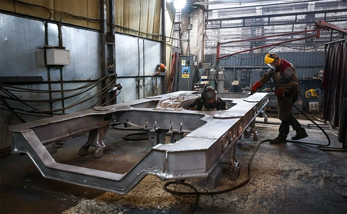 рабочие обрабатывают металлическую раму