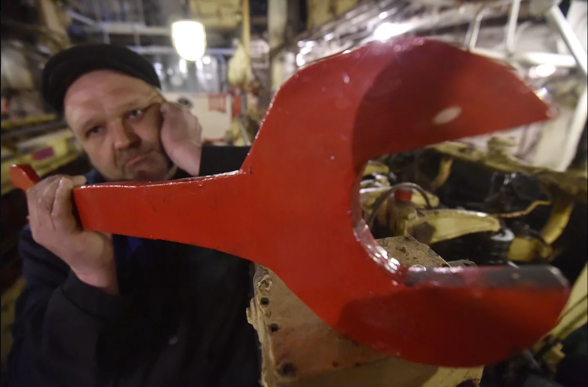 рабочий держит большой гаечный ключ