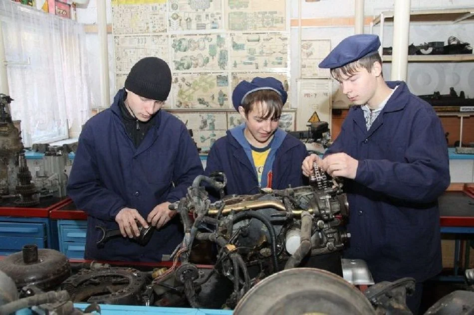 учащиеся ПТУ перебирают двигатель в мастерской