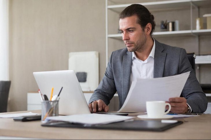 сотрудник офиса за ноутбуком и с бумагами