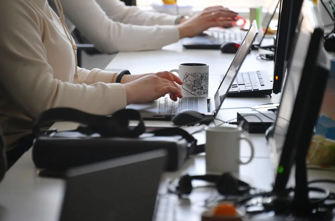 сотрудники набирают текст на клавиатуре ноутбуков