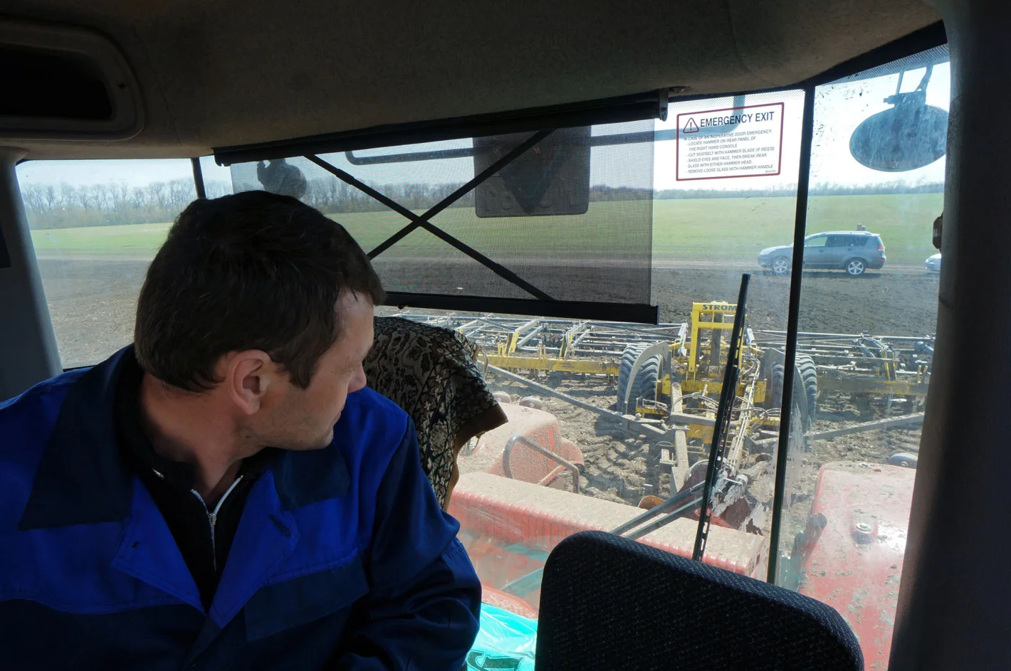 тракторист сидит в кабине и следит за обработкой почвы