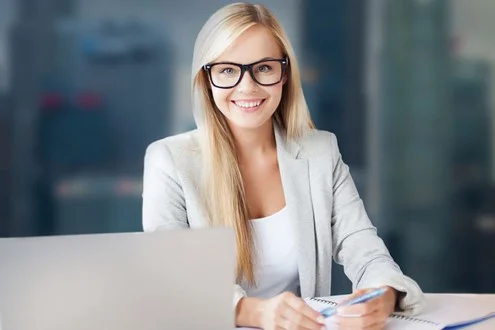 Девушка бухгалтер на первичную документацию сижит за столом в офисе и держит ручку