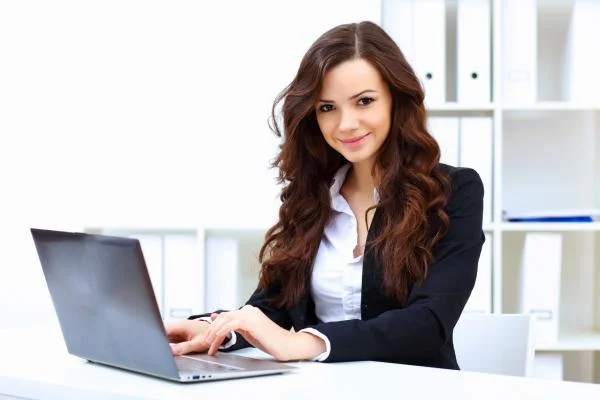 Девушка бухгалтер сидит за столом и работает с ноутбуком