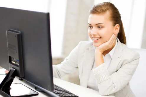 Девушка бухгалтер на участок банк-клиент в пиджаке работает за компьютером в офисе