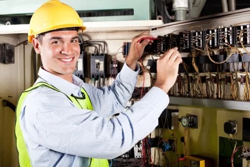 Мужчина инженер по эксплуатации в каске работает с электрикой
