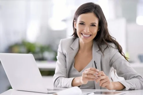 Девушка финансовый аналитик сидит за столом с ноутбуком и ручкой