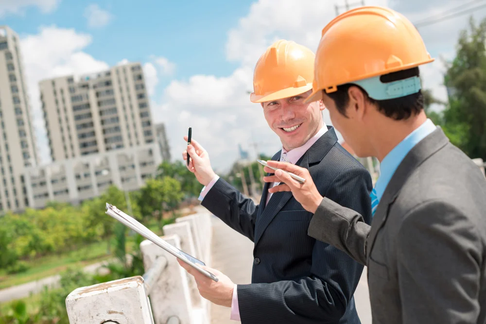 Мужчина главный инженер в каске на мосту показывает сотруднику недвижимость