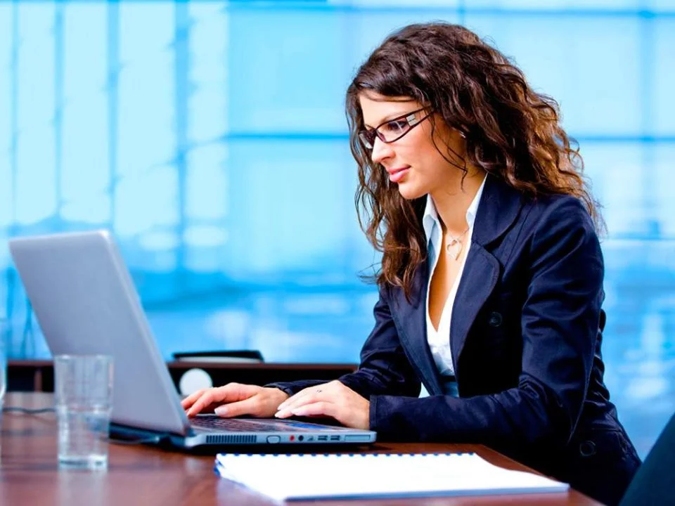 Девушка импорт-менеджер работает в офисе за столом с ноутбуком