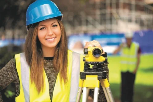 Девушка инженер геодезист стоит с оборудованием