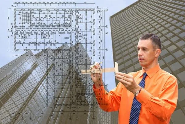 Мужчина инженер-конструктор проводит замеры линейкой по схеме на фоне зданий