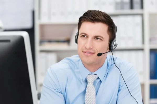 Мужчина инженер технической поддержки с микрофоном сидит в офисе