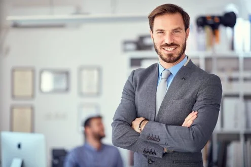 Мужчина коммерческий директор стоит скрестив руки в офисе