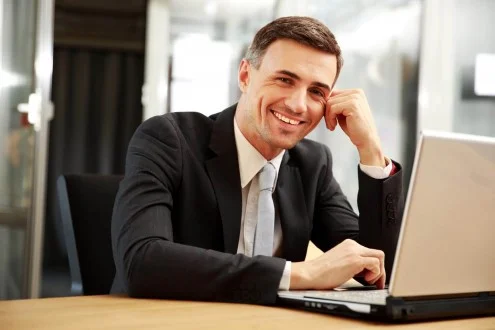 Мужчина коммерческий директор в костюме сидит за столом с с ноутбуком