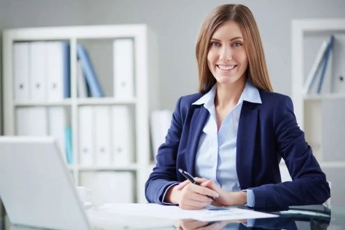 Девушка менеджер по подбору персонала сидит в офисе за столом с ноутбуком и документами