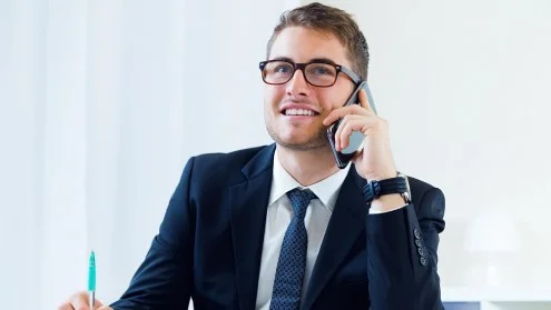 Мужчина менеджер по продажам в очках сидит и разговаривает по телефону