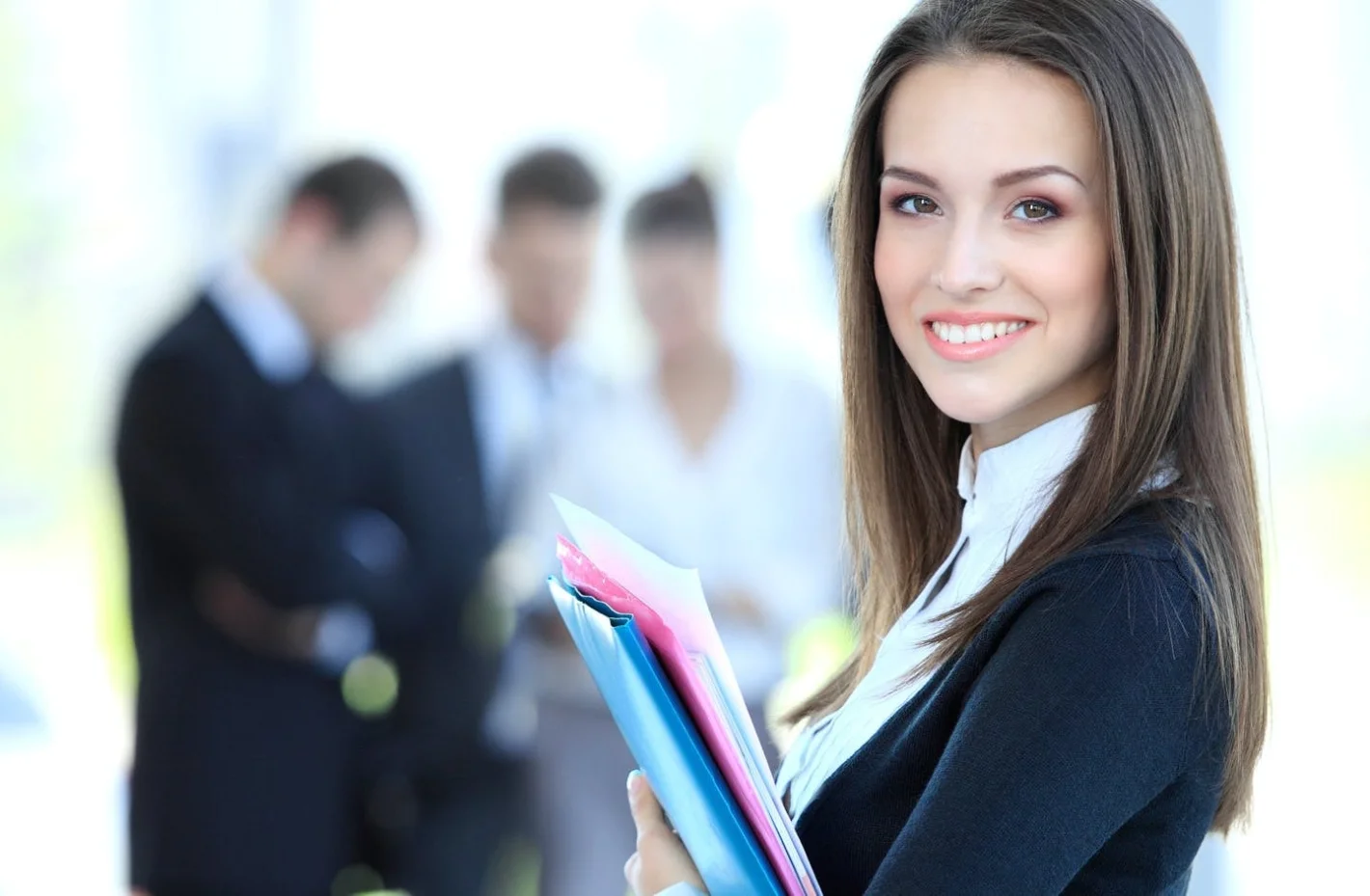 Девушка менеджер по персоналу стоит с папками на фоне сотрудников