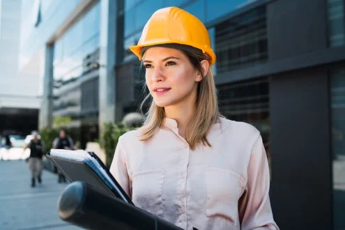 Девушка помощник ГИПа стоит с документами на фоне здания