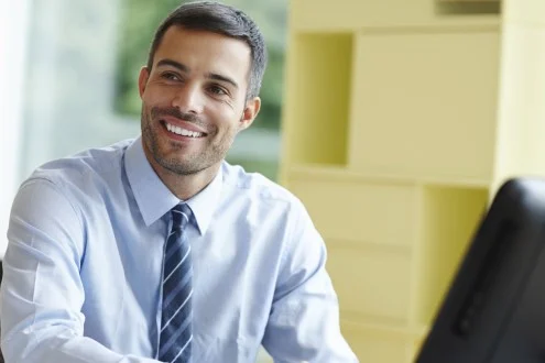 Мужчина системный аналитик сидит в офисе за компьютером